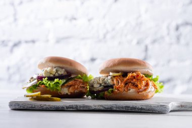 Baharatlı tavuk Burger domates ve Beyaz ahşap tahta üzerinde turşu ile