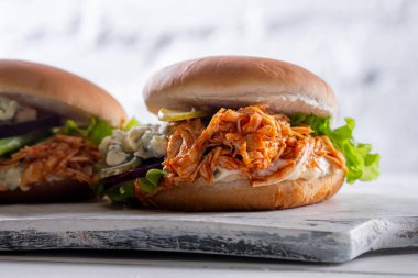 Baharatlı tavuk Burger domates ve Beyaz ahşap tahta üzerinde turşu ile