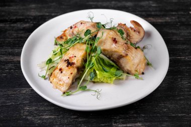 Fırında beyaz balık dilimleri ile baharat beyaz plaka üzerinde yeşil bezelye filizi ile