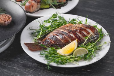Bütün yeşil salata yastık üzerinde limon dilimleri ile servis balık pişmiş 
