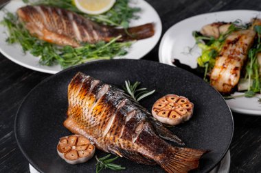 Biberiye dallar ile taze bütün pişmiş balık fırında sarımsaklı tabakta servis