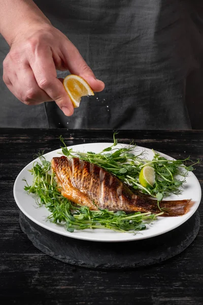 Seorang Pria Menaburkan Jus Lemon Pada Ikan Panggang Pada Salad — Stok Foto