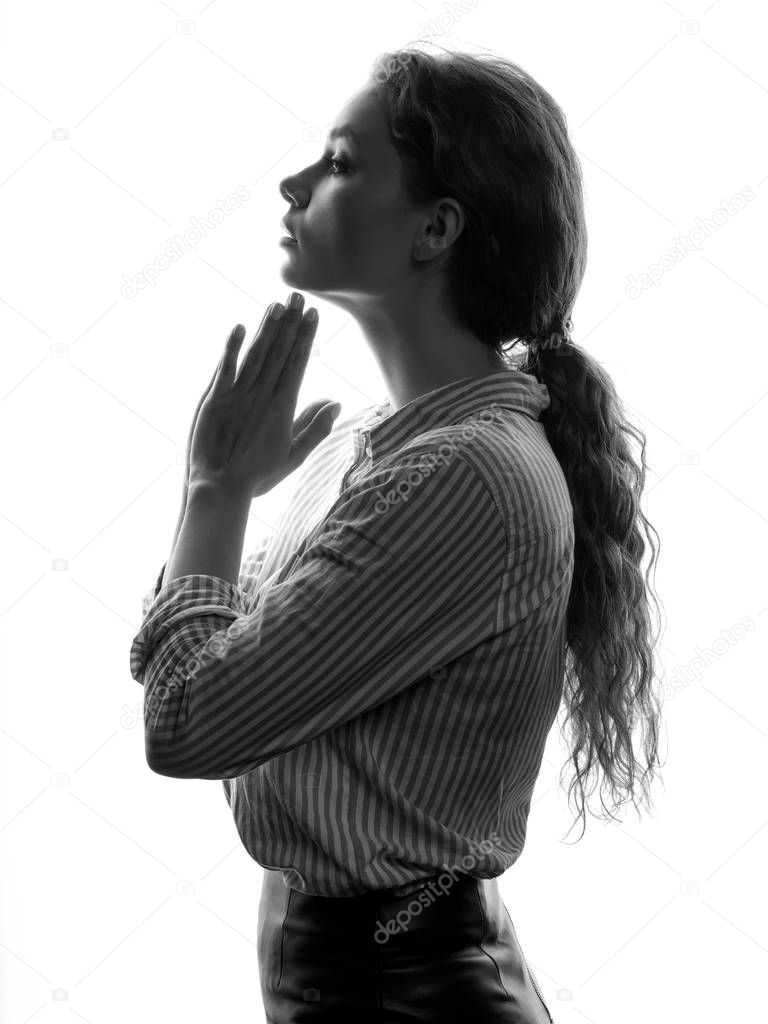 Portrait of young curly woman in striped shirt holding hands in praying gesture on white background