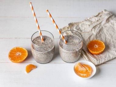 Ahşap beyaz zemin üzerine gözlüklü olgun mandalina ile ev yapımı chia puding