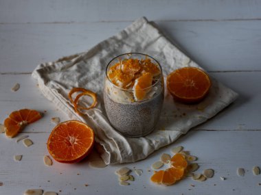 Beyaz ahşap zemin üzerinde taze ev yapımı chia puding olgun mandalina ve kuşbaşı badem ile Görünümü Kapat