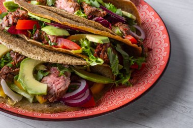 Beyaz ahşap arka plan üzerinde kireç dilimi ile servis sığır eti, avokado dilimleri ve biber ile taze tacos 