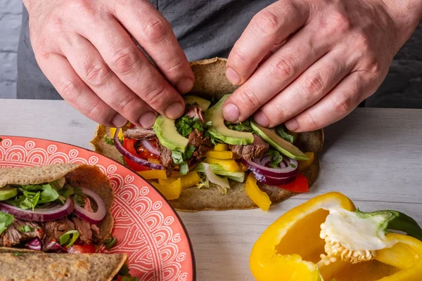 Ahşap masada avokado ve sığır eti ile tacos pişirme erkek şefin yakın görünümü 