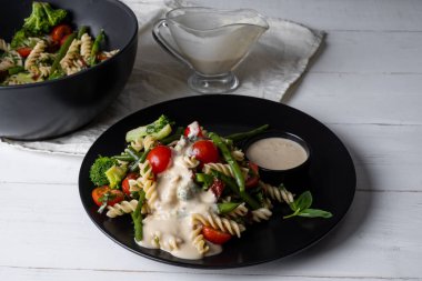 Kase ve beyaz ahşap masada makarna ve sebze ile sıcak salata dolu tabak