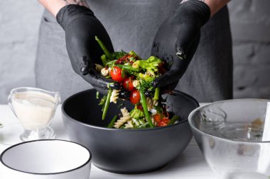 Makarna ve sebze ile sıcak salata karıştırma erkek şef in yakın görünümü 