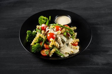 Beyaz tabakta kremalı beyaz sos ile servis makarna ve sebze ile Sıcak salata