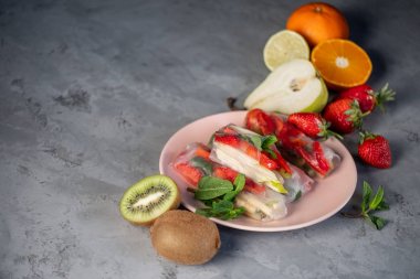 Gri taş arka plan üzerinde tabakta çilek, elma, armut ve kivi ile meyveli börek yakın görünümü