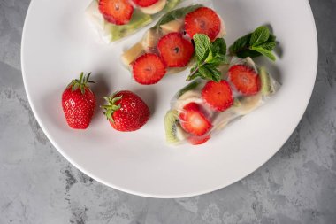 Gri taş arka plan üzerinde tabakta çilek, elma, armut ve kivi ile meyveli börek yakın görünümü