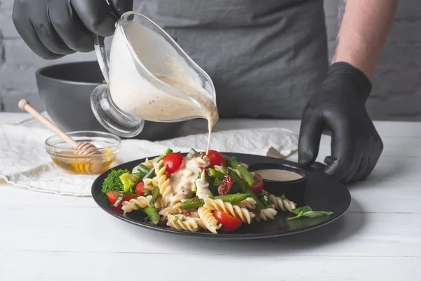 Vue Rapprochée Homme Versant Sauce Crémeuse Sur Une Salade Pâtes — Photo