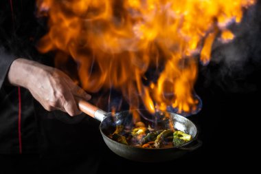 Siyah arka planda tavada yanan sebzelerin yakın görünümü  