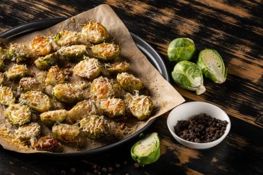 Koyu ahşap masada parmesan peynirli taze pişmiş brüksel lahanası 