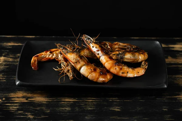 Close view of spicy grilled tiger shrimps on black plate