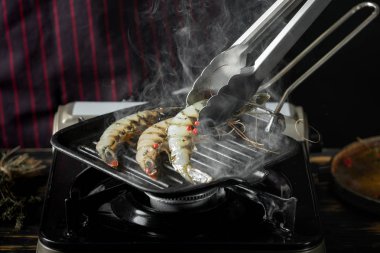 Izgara tavada baharatlı soslu çiğ karides ızgara erkek şef in yakın görünümü 