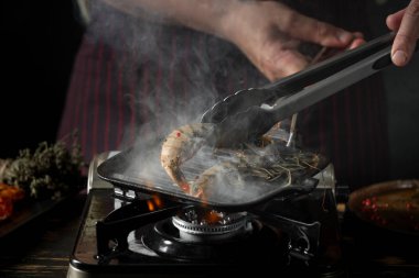 Izgara tavada baharatlı soslu çiğ karides ızgara erkek şef in yakın görünümü 