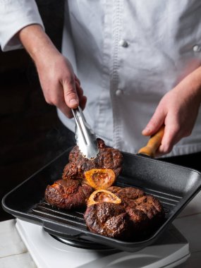 Izgara tavada baharatlı biftek pişiren şef