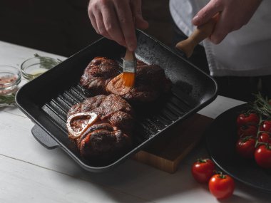 Sığır biftek üzerinde pişirme fırçası ile erkek şef yağlama sosu yakın görünümü