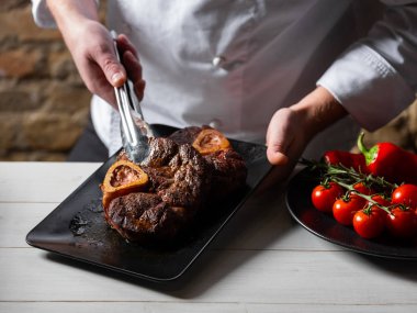 Şef siyah plaka üzerine taze ızgara sığır biftek koyarak