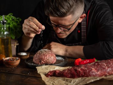 Şef baharat ve otlarla doğranmış çiğ et hazırlıyor.