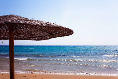 Corfu Yunanistan bir güzel kumlu plajda thatched saman şemsiye. Deniz kıyısı hoş manzara. Sahil temiz mavi su. Yaz tatil zamanı. Rahatlatıcı moment sandalye ve şemsiye