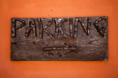 İşareti otopark. Rustik ahşap kurulları ile oyulmuş mektup ve turuncu duvar oku. Gösterge park araçlara kamusal alan için. Yol tarifi. Ahşap oyma işaretleri