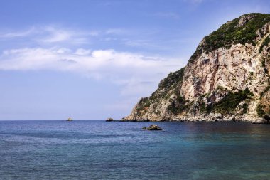 Turkuaz denizin masmavi gökyüzünde sakin ve yalnız bir tatil için ideal bir yerdir. Arka planda bir kaç hillocks ve yeşilimsi bir top ile bir tepe vardır.