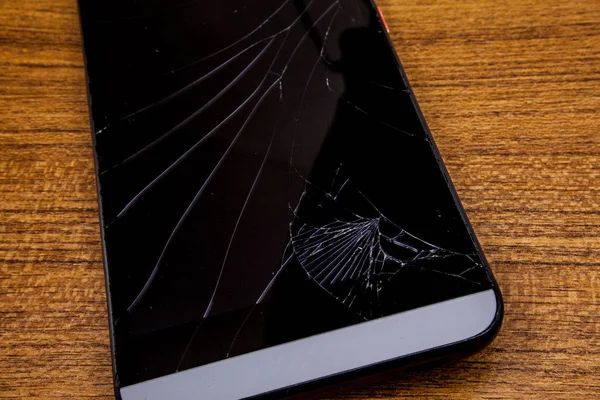 Masanın üzerine düşen cep telefonu. Siyah cep telefonu çöktü lcd ile ahşap tabloda görüntüler. Smartphone portre görünümünde yok. Mobil teknoloji kavramı.