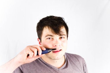 Genç adam, düzeltici ile onun burun saç kaldırın. Yakışıklı delikanlı ile elektrikli tıraş makinesi burun kılı kaldırır. Güzellik ve insanlar kavramı. Erkek kesme kıllar elektrik makası kullanarak burun