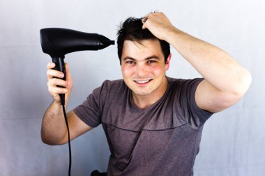 Onun saç kurur iken gülümseyen genç. Saç üfleyici tutan adam. Genç adam, vantilatör ile saç kurur. Bir saç kesimi için bir gece hayatı gidiş için hazırlanıyor