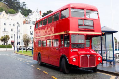 Llandudno, Galler, İngiltere - 27 Mayıs 2018 Londra'nın kırmızı çift katlı araba yolun üzerine park etmiş. otobüs durağı. Turizm ve efsanevi çift katlı otobüs ile turistik seyahat. Kırmızı araç