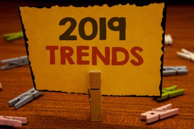 2019 eğilimleri metinleri yazma kelimeler. Moda değişiklikleri yenilikler Modernclothespin gelişmeler yeni yıl için iş kavramı tutun clothespins ahşap arka plan sarı kağıt fikirler holding