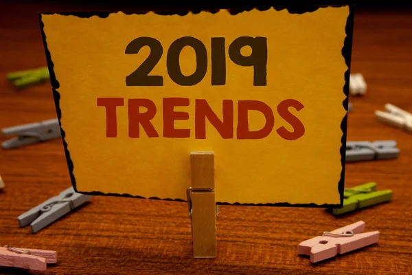 2019 eğilimleri metinleri yazma kelimeler. Moda değişiklikleri yenilikler Modernclothespin gelişmeler yeni yıl için iş kavramı tutun clothespins ahşap arka plan sarı kağıt fikirler holding
