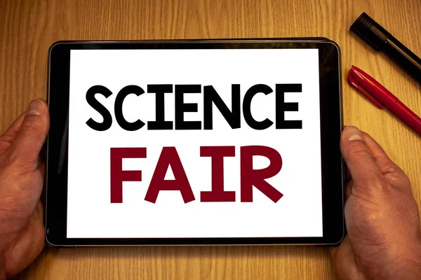 Text sign showing Science Fair. Conceptual photo School competition where contestants present projectsMan hold holding table with ideas words white screen black red pens wooden