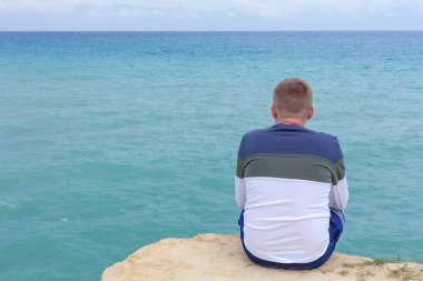 Cliff üzerinde oturan adam. Turist ovelooking açık deniz. Shoaling dalgalar ve approcahing deniz dibinin. Tropikal hedef rahatlatıcı. Gezi ve açık besleyicisini etkinliği