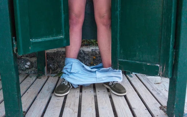 Açık kapı arkasında duran bir adam. Bacaklarını ahşap yere aşağı düşen adam iç çamaşırı. An fotoğraf çalmak. Yetişkin teaser görüntü