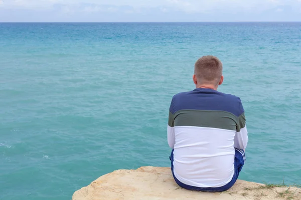 Cliff üzerinde oturan adam. Turist ovelooking açık deniz. Shoaling dalgalar ve approcahing deniz dibinin. Tropikal hedef rahatlatıcı. Gezi ve açık besleyicisini etkinliği