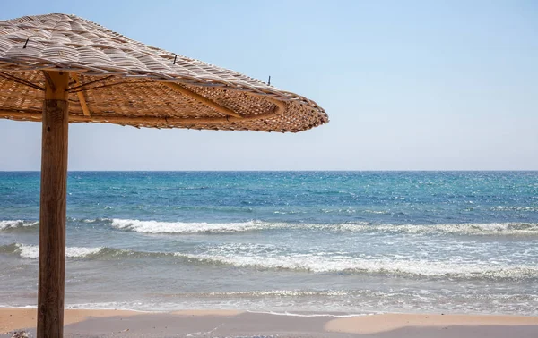 Uzun boylu şemsiye ayakta kum. Kıyı gölge veren ahşap Bonita kulübe. Denizin shinning parlak bir güneş. Seyahat hedef rahatlatıcı. Beach fikirler