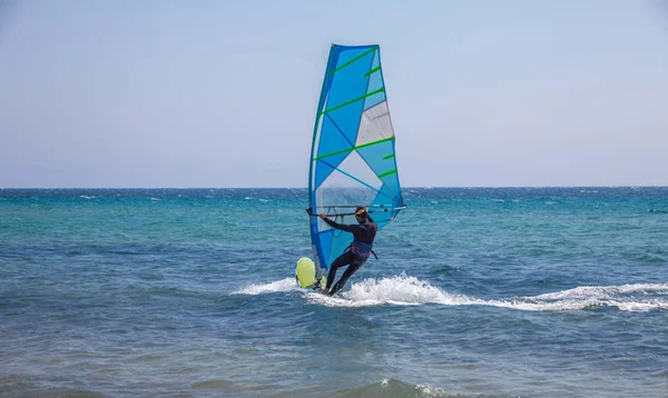 Yelken kurulu Dengeleme bir adam. Güçlü dalgalar su spor ekipmanları kayma. Rüzgar Sörfü tutkunu eylem. Plaj etkinliği teşvik