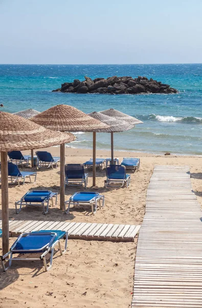 Okyanusa karşı odun lifi yol ortak splice. Ahşap kulübe arasında bir yürüyüş kurulu geçiş. Portatif sandalye plaja bakan. Su üstünde ikonik kaya oluşumu. Turizm