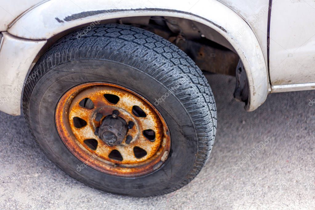 Rust covering the entire rim of a car. Depth scratches stretching in the vehicle guard.Slanting parking position. Maintenance and repair of a ground transportation