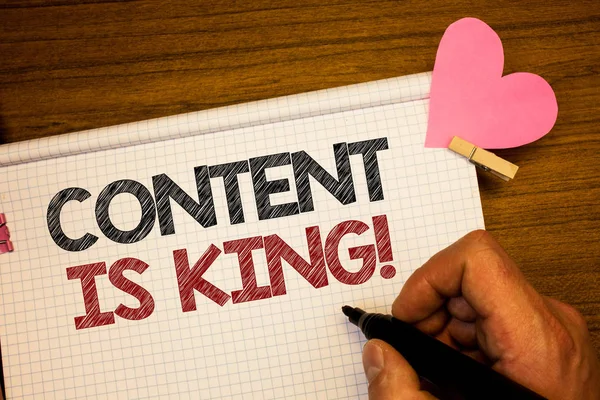 İçerik kral motivasyonel çağır gösterilen Not yazma. Pazarlama bilgi reklam stratejisi kalem fikirler defter pembe kalp harf ahşap arka plan üzerinde tutan adam vitrine iş fotoğraf