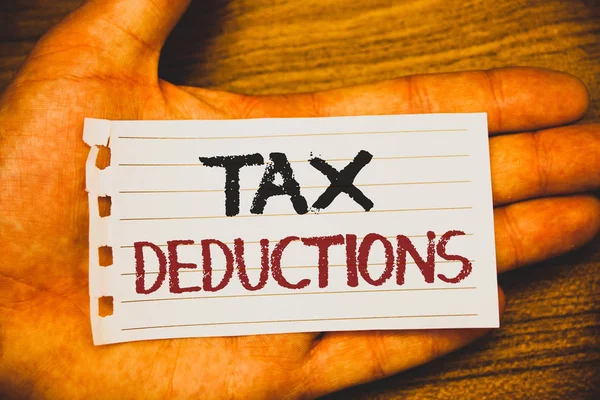 Handwriting text writing Tax Deductions. Concept meaning Reduction on taxes Investment Savings Money Returns Text two Words written white paper note hand open palm pencil message