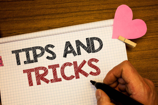 Writing note showing  Tips And Tricks. Business photo showcasing Suggestions to Make things easier Helpful Advices Solutions Man holding pen ideas notebook pink heart letters on wooden background
