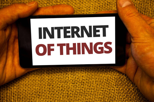 Text sign showing Internet Of Things. Conceptual photo Innovation Globalization Digital Electronics Connectivity Jute sack background hand holding iPhone with colorful alphabetic syllable