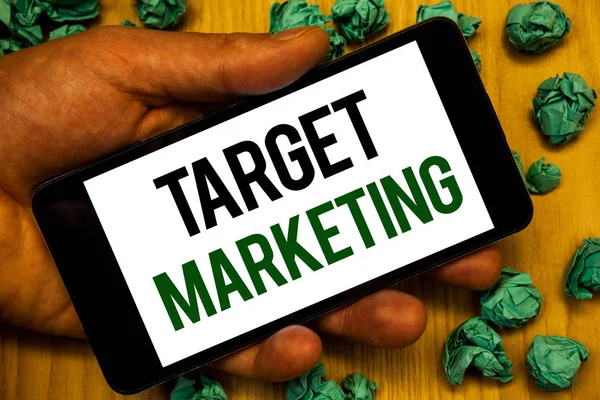 Handwriting text Target Marketing. Concept meaning Market Segmentation Audience Targeting Customer Selection Hand holding phone white screen written words crumbled green notes paper