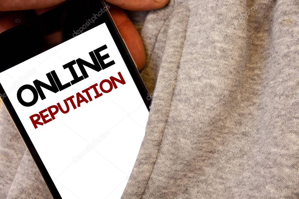 Text sign showing Online Reputation. Conceptual photo Reliability Ranking Review Evaluation Satisfaction Quality Words written black Phone white Screen Hand holding pocket white tracksuit