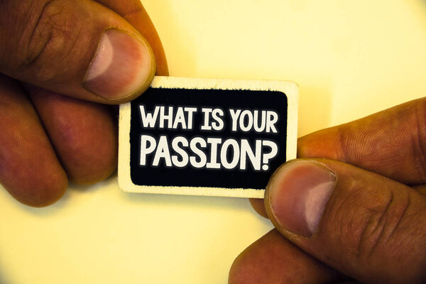 Текст, написанный словом "Что тебя интересует?". Бизнес-концепция для того, чтобы спросить кого-нибудь о его мечтах и надеждах Две руки держат в руках маленькую черную карту, сосредоточенную на белом сером фоне массажа
